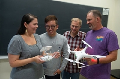Adriana E. Martinez, PhD, assistant professor in the Department of Geography, is the instructor for the FAA Remote Pilot Certification course. Martinez talks to students in the fall course (L-R) Mingshao Zhang, PhD, assistant professor in the Department of Mechanical and Industrial Engineering; and Donald Anderson, engineering draftsman II; and John Renken, architect II, both in Facilities Management.